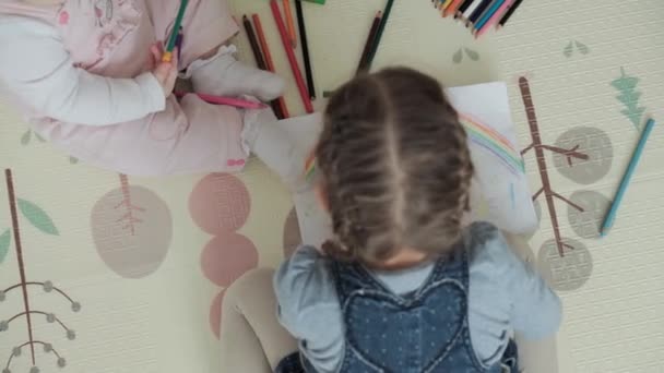 Autentici due bambini creativi sorellina felice bambino con mamma disegnare da matite primavera venuta immagine arcobaleno divertirsi sul pavimento al chiuso in sala giochi. Infanzia, Arte, educazione, Creatività, concetto di maternità — Video Stock