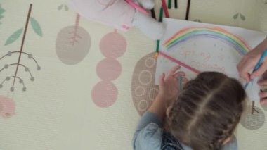 Otantik iki mutlu kardeş yaratıcı çocuklar anneleriyle birlikte kalemle çiziyorlar bahar geliyor resim gökkuşağı içeride, oyun odasında yerde eğleniyor. Çocukluk, Sanat, Eğitim, Yaratıcılık, annelik kavramı