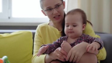 Beyaz tenli genç annenin gerçek yakın plan çekimleri kollarını tutuyor, ayak egzersizleri yapıyor evde yeni doğan bebek için hareketlilik üzerine şarkılar söylüyor. bebek, annelik, çocukluk, aile, özgünlük konsepti