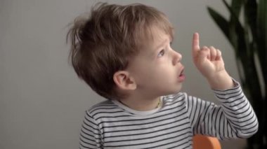 Otantik küçük anaokulu çocuğu kameraya bakar ve dudaklarını ve ağzını işaret eder. Yüzünde siğil ya da yumuşakça olan hasta bir çocuğun portresi. Tıp ve sağlık, pediatri konsepti
