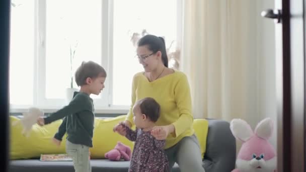 Autentisk närbild av unga neokaukasiska mamma leka med två små barn spädbarn baby flicka och förskola pojke ha kul tillbringa tid hemma inomhus. moderskap, barndom, familj, äkthet begrepp — Stockvideo