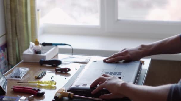 Mãos masculinas fixando laptop, aparafusar parafusos de tampa traseira com chave de fenda. serviço de reparação eletrônica. técnico que trabalha no escritório. a reparar o telefone. engenharia, avaria, conceito de tecnologia avançada — Vídeo de Stock