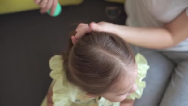 在黄色的灰色沙发上，把真正可爱的年轻的高加索女人妈妈照看孩子辫子的照片贴在金发碧眼的头发上。编织编织的过程。时尚与美，母性观念 — 图库视频影像