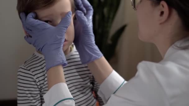 Primer plano mujer médico dermatólogo en guantes azules exprime espinilla 3-4 años menor niño preescolar. Sobre el hombro enfermera tiro trata el acné en el niño. medicina y salud, concepto de pediatría — Vídeo de stock