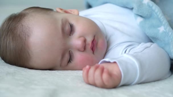 Authentique gros plan de mignon caucasien petit bébé chubby enfant fille dormir doucement dans un lit blanc confortable recouvert d'une couverture bleue. Garde d'enfants, Bébé au lit, Enfance, Parentalité, concept de vie — Video