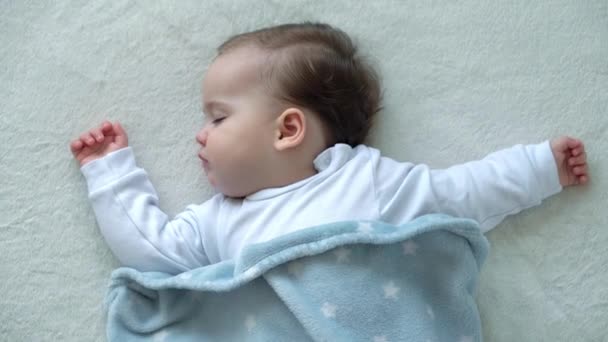 Autêntico close-up de bonito caucasiano pequena criança gordinha menina dormir docemente em confortável cama branca coberta com cobertor azul. Cuidados com a criança, Bebê adormecido, Infância, Paternidade, conceito de vida — Vídeo de Stock