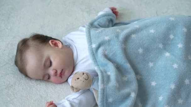Auténtico primer plano de lindo bebé caucásico gordita niña duerme dulcemente en cómoda cama blanca y azul con oso de peluche. Cuidado de niños, Niñez dormida, Infancia, paternidad, concepto de vida — Vídeos de Stock