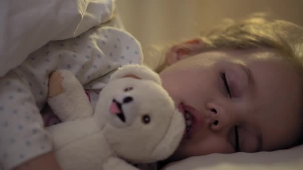 Autentické zblízka roztomilé kavkazské malé školky batole dítě dívka 3-4 roky sladce spát v pohodlné bílé posteli s plyšovým medvídkem. Péče o děti, Spící miminko, Dětství, Rodičovství, Životní koncept — Stock video