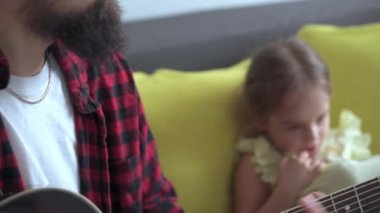 Rock tarzında mutlu bir adam, küçük çocukla rahat evinde gitar çalarak vakit geçirir. Baba küçük tatlı kız için şarkılar söyler müzik enstrümanı yerli müzik dersinin keyfini çıkar. aile, aşk, hayat konsepti