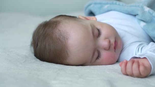 Autentico primo piano di carino caucasico piccolo bambino paffuto ragazza dormire dolcemente in comodo letto bianco coperto con coperta blu. Cura dei bambini, Bambino che dorme, Infanzia, Genitorialità, concetto di vita — Video Stock