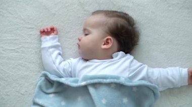 Beyaz, şirin, beyaz, tombul bir kızın otantik yakın çekimi. Mavi battaniyeyle kaplı beyaz yatakta tatlı tatlı uyur. Çocuk bakımı, Uyuyan Bebek, Çocukluk, Ebeveynlik, Yaşam Konsepti