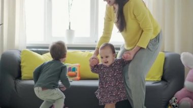 Genç neo beyaz annenin iki küçük çocukla oynadığı sahici yakın plan bebek kız ve anaokulu çocuğu evde eğleniyor. annelik, çocukluk, aile, özgünlük kavramı