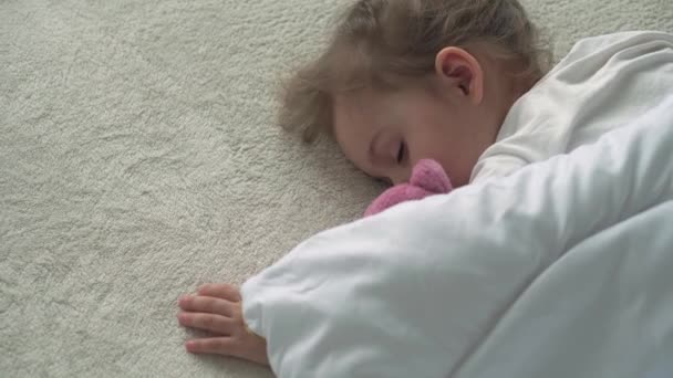 3-4 년된 귀여운 코카서스 아기가 테디 베어 와 함께 편안 한 흰색 침대에서 편안하게 잠을 자는 것은 확실하게 가까운 일이다. 자녀 양육, 잠 자는 아기, 어린 시절, 부모로서의 삶의 개념 — 비디오
