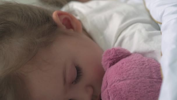 Otentik menutup anak-anak di TK yang lucu simpul anak laki-laki dan perempuan tidur manis di tempat tidur putih yang nyaman dengan boneka beruang. Perawatan anak, Bayi tidur, masa kanak-kanak, orang tua, konsep kehidupan. — Stok Video