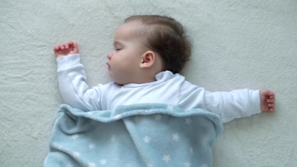 Autentické zblízka roztomilé kavkazské malé baculaté dítě dívka spát sladce v pohodlné bílé posteli pokryté modrou přikrývkou. Péče o děti, Spící miminko, Dětství, Rodičovství, Životní koncept — Stock video