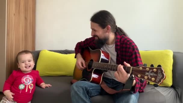 Boldog kis aktív csecsemő aranyos baba tánc. A család otthon gitározik. Apa megtanítja a kisfiút hangszeren játszani, élvezi a házi zenét. oktatás, életkoncepció — Stock videók