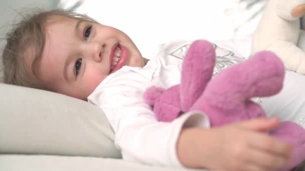 Authentic close up cute caucasian little preschool toddler child girl sleepy upon waking with teddy bear looking at camera in white bed. Child care, Sleeping baby, Childhood, Parenthood, life concept — Stock Video