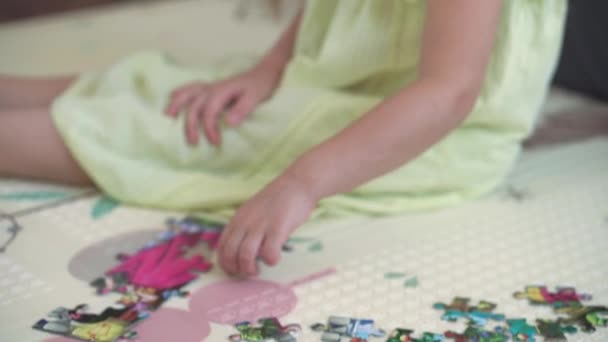 Auténtica niña linda y feliz preescolar pone rompecabezas en el suelo de cerca. niño pequeño juega solo juegos educativos para las habilidades motoras cerca de sofá gris amarillo. Infancia, familia, concepto de aislamiento. — Vídeos de Stock