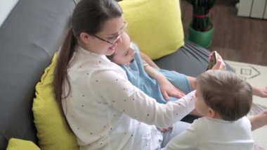 Kafkas ailesi küçük çocukları kız çocuk ve anne akıllı telefonlarıyla video konferansında evdeki oturma odasında mutluluk gülümsemesiyle sohbet ediyorlar. faaliyet teknolojisi yaşam tarzı cep telefonu kullanımı kavramı