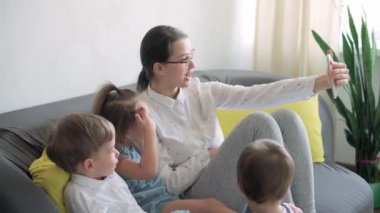 Kafkas ailesi küçük çocukları kız çocuk ve anne akıllı telefonlarıyla video konferansında evdeki oturma odasında mutluluk gülümsemesiyle sohbet ediyorlar. faaliyet teknolojisi yaşam tarzı cep telefonu kullanımı kavramı