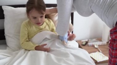 yakın plan otantik beyaz kadın hemşire ya da doktor çocuk doktoru bebek kızı muayene eder ve oyuncak ayıyı beyaz yatağa verir. Annem hasta çocuğa bakıyor. tıp ve sağlık, annelik, covid-19 kavramı