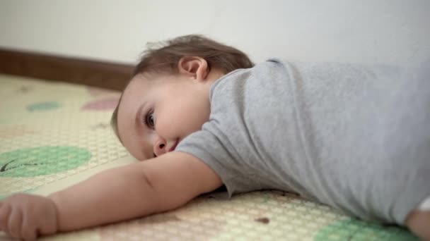 Fermer enfant authentique chubby fille enfant avec croix sur la poitrine promenades maladroites et rampe. petit enfant jouer seul jeux éducatifs apprendre à marcher dans la salle de jeux. Enfance, famille, concept d'isolation — Video