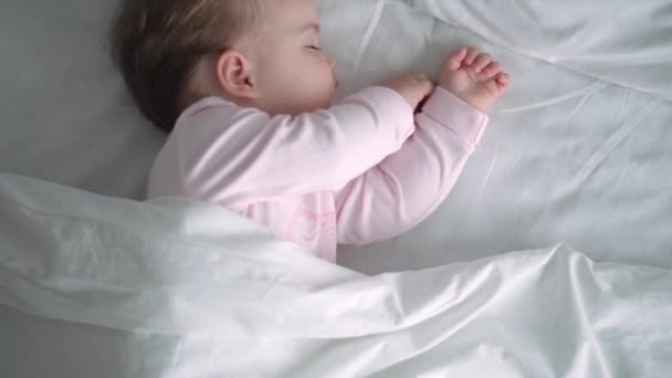 Auténtico retrato lindo bebé caucásico regordete niña o niño en sueño rosa con oso de peluche en la cama blanca. niño descansando a la hora del almuerzo. cuidado, Niñez durmiente, Infancia, paternidad, concepto de vida — Vídeo de stock