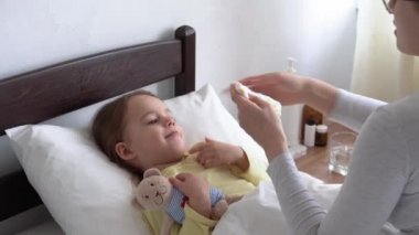 Yakın plan beyaz kadın hemşire ya da doktor çocuk doktoru bebeği muayene eder ve beyaz yatağa baskı uygular. Annem hasta çocuğa bakıyor. tıp ve sağlık, annelik, covid-19 kavramı