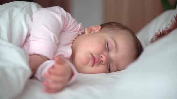 Authentique portrait mignon caucasien petit bébé joufflu bébé fille ou garçon dans le sommeil rose avec ours en peluche sur lit blanc. enfant se reposant à l'heure du déjeuner. soins, Enfant au lit, Enfance, Paternité, concept de vie — Video