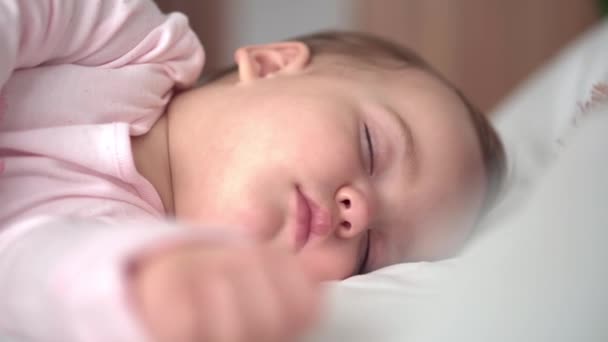 Äkta porträtt söt kaukasiskt litet spädbarn knubbig liten flicka eller pojke i rosa sömn med nalle på vit säng. Barnet vilar vid lunchtid. vård, Sömnunge, Barndom, Föräldraskap, livskoncept — Stockvideo