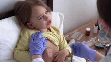 Otantik şirin beyaz kadın hemşire ya da doktor çocuk doktoru hastanede beyaz yatakta statoskop minör anaokulu çocuğu ile muayene ediyor. ilaç ve sağlık, pediatri, covid-19 konsepti