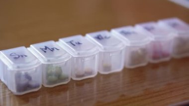 Haftanın her günü siyah kalemli haplar için plastik organizatör kutusuna yakın mesafeden yeniden odaklanıyor. Geleneksel ve Alternatif Tıp ve Sağlık, Hastalık, Salgın, covid-19 kavramı