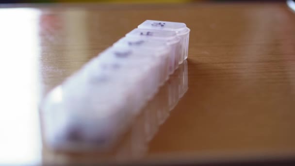 Heroriëntering van verre naar nabije van plastic organisator doos voor pillen met cellen gemarkeerd zwarte marker op dagen van de week. Traditionele en alternatieve geneeskunde en gezondheid, ziekte, pandemie, covid-19 concept — Stockvideo