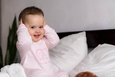 Otantik beyaz portre, pembe uykulu küçük tombul kız bebek ya da beyaz yatakta tatlı tatlı gülümseyen ve somurtan kameraya bakarak uyanan oğlan. Çocuk bakımı, Çocukluk, Ebeveynlik, hayat konsepti