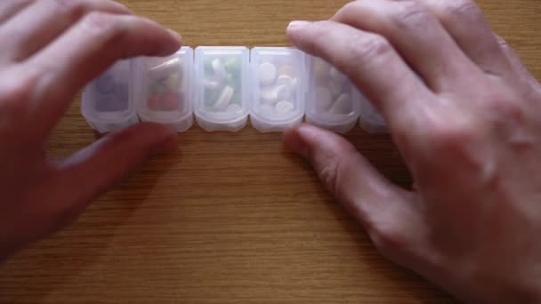 Extrem närbild av manliga händer fingrar tar piller från plast arrangör box. Någon sjuk man som söker bot i medicinplaneraren. Traditionell och alternativ medicin och hälsa, covid-19 konceptet — Stockvideo