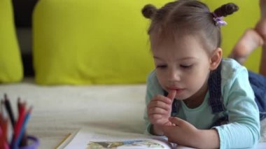 Arkadaşlık, aile, eğitim, akıllı, gülümseyen bir okul çocuğu, küçük kız sarı yatakta büyük, ilginç masallar okuyor. Küçük sevimli okuyucu evde karantinada eğleniyor, mutlu çocuk.