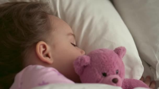 Authentisch süße kaukasische kleine Vorschulgeschwister Baby Junge und Mädchen in blau rosa Pyjama schlafen mit Teddybär auf weißem Bett. Kindererholung, Pflege, Medizin und Gesundheit, Kindheit, Lebenskonzept — Stockvideo