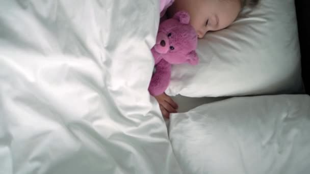 Authentisch süße kaukasische kleine Vorschulgeschwister Baby Junge und Mädchen in blau rosa Pyjama schlafen mit Teddybär auf weißem Bett. Kindererholung, Pflege, Medizin und Gesundheit, Kindheit, Lebenskonzept — Stockvideo