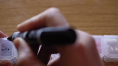 Erkek el parmaklarının kapatılması hücreleri haftanın günlerinde plastik hap organizatörü kutusunda siyah kalemle işaretler. Tedavi arayan hasta bir adam. Geleneksel ve Alternatif Tıp ve Sağlık, covid-19 kavramı