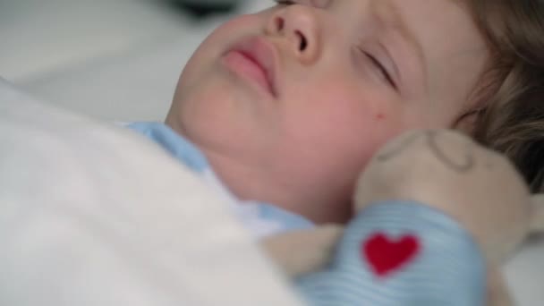 Auténtico retrato lindo caucásico pequeños hermanos preescolares bebé y niña en pijama rosa azul dormir con oso de peluche en la cama blanca. descanso infantil, cuidado, medicina y salud, Infancia, concepto de vida — Vídeo de stock