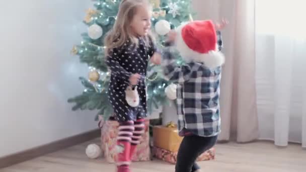 3 niños felices auténticos alegría saludar de la mano regocijarse por el juego del árbol de Navidad divertirse juntos. Los niños preescolares celebran el ambiente festivo de Año Nuevo en casa. Invierno, vacaciones, concepto familiar — Vídeos de Stock