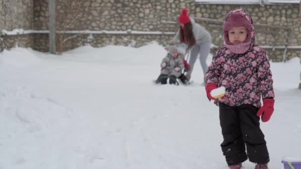 Winter, vakantie, spel, familie concept - algemeen plan authentieke kleine kleuterschool minderjarige 3-4 jaar oud meisje in het paars op besneeuwde weide tuin bedacht staat en kijkt naar de camera. kind op besneeuwd gebied — Stockvideo