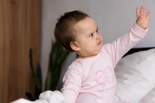 Authentisches Porträt niedlichen kaukasischen kleinen Säugling pummelig Baby Mädchen oder Junge in rosa schläfrig beim Aufwachen Blick in die Kamera im weißen Bett. Kinderbetreuung, Kindheit, Elternschaft, Lebensstilkonzept — Stockfoto