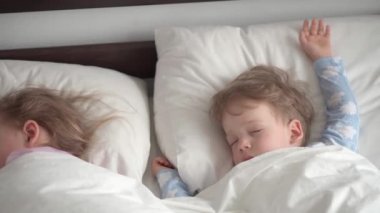 Otantik portre 2 şirin beyaz anaokulu kardeşleri mavi pijamalı kız ve erkek bebek beyaz yatakta oyuncak ayıyla uyuyorlar. çocuk istirahati, bakım, ilaç, sağlık, çocukluk, yaşam konsepti