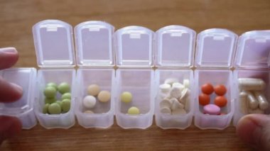 Erkek parmaklarının plastik organizatör kutusundan hap almasına çok az kaldı. İlaç planlayıcısında tedavi arayan hasta bir adam. Geleneksel ve Alternatif Tıp ve Sağlık, covid-19 kavramı