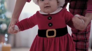 Noel Baba şapkası ve şöminenin yanında kırmızı elbisesi olan, otantik, tombul, bebek bebek bebek annesi Noel ağacının yanında yeni yılı kutluyor. Çocukluk, Ebeveynlik, Bayram, Kış Konsepti.
