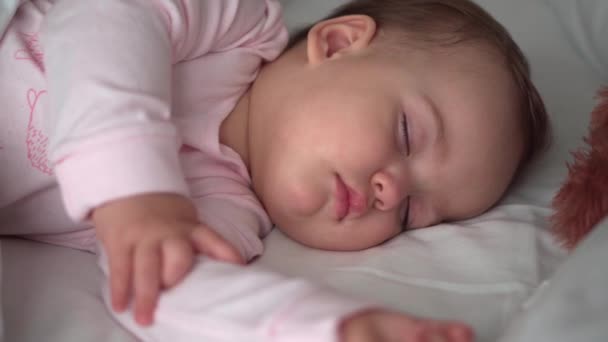 Autentyczne portret cute kaukaskie małe dziecko pucołowate dziewczynka lub chłopiec w różowym śnie z misiem na białym łóżku. dziecko odpoczywa w porze lunchu. opieka, Śpiący dzieciak, Dzieciństwo, Rodzicielstwo, koncepcja życia — Wideo stockowe