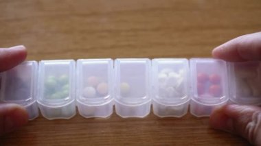 Erkek parmaklarının plastik organizatör kutusundan hap almasına çok az kaldı. İlaç planlayıcısında tedavi arayan hasta bir adam. Geleneksel ve Alternatif Tıp ve Sağlık, covid-19 kavramı