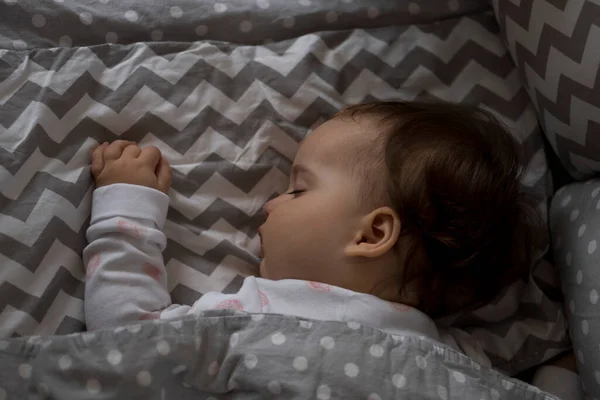 Top view Söt liten knubbig liten flicka unge sover sött i grå babysäng under lunchen vilotid i vit och rosa pyjamas med nalle hemma. Barndom, fritid, komfort, medicin, hälsa koncept — Stockfoto