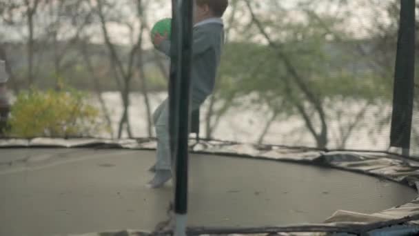 Primavera, deporte, día de fiesta, familia, infancia - cámara lenta Tres hermanos preescolares niños pequeños felices niños gemelos jugar divertirse saltar bolas en trampolín al aire libre soleado atardecer en el parque — Vídeo de stock